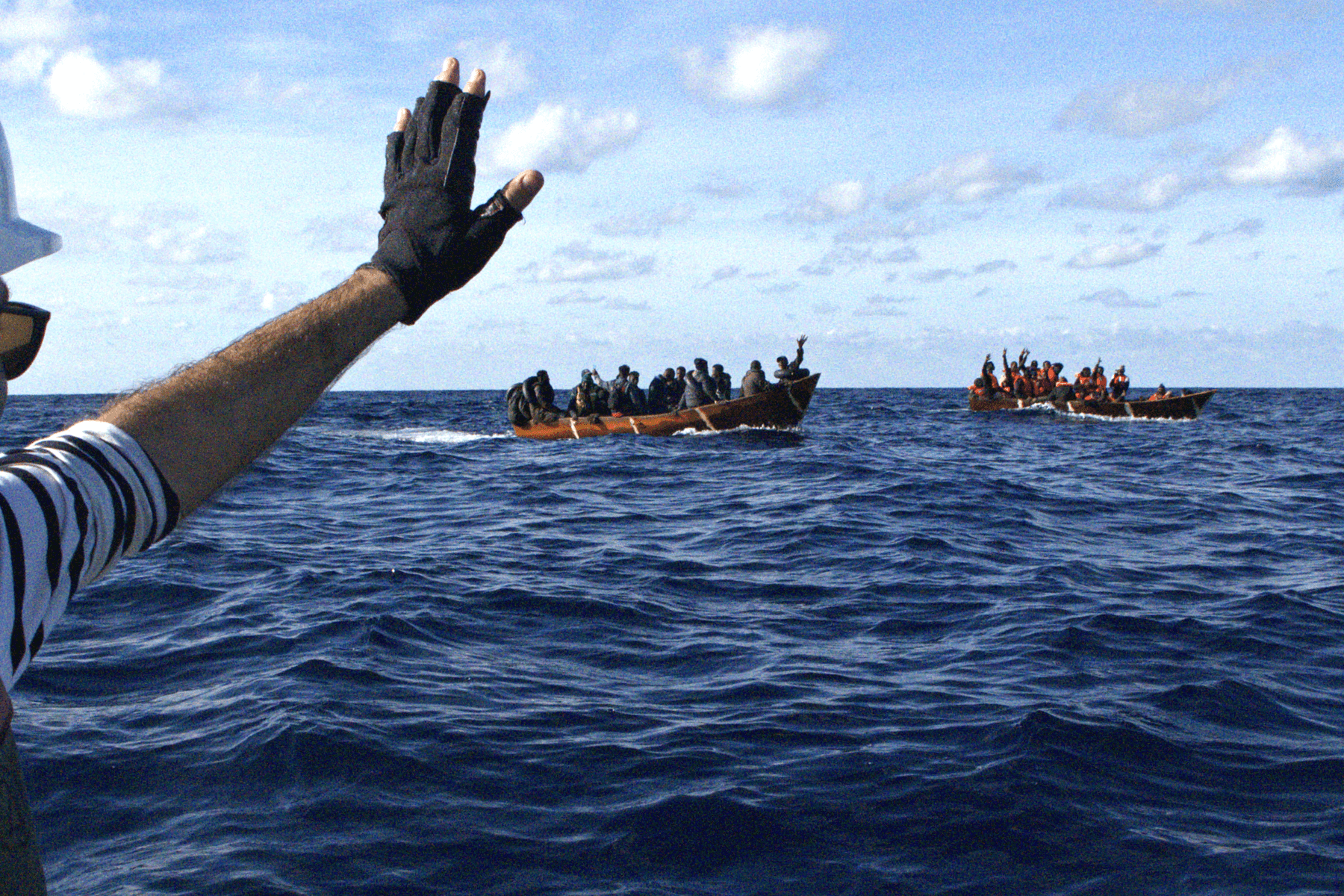 Nadir-Crew-winkt-Menschen-in-Flüchtlingsbooten