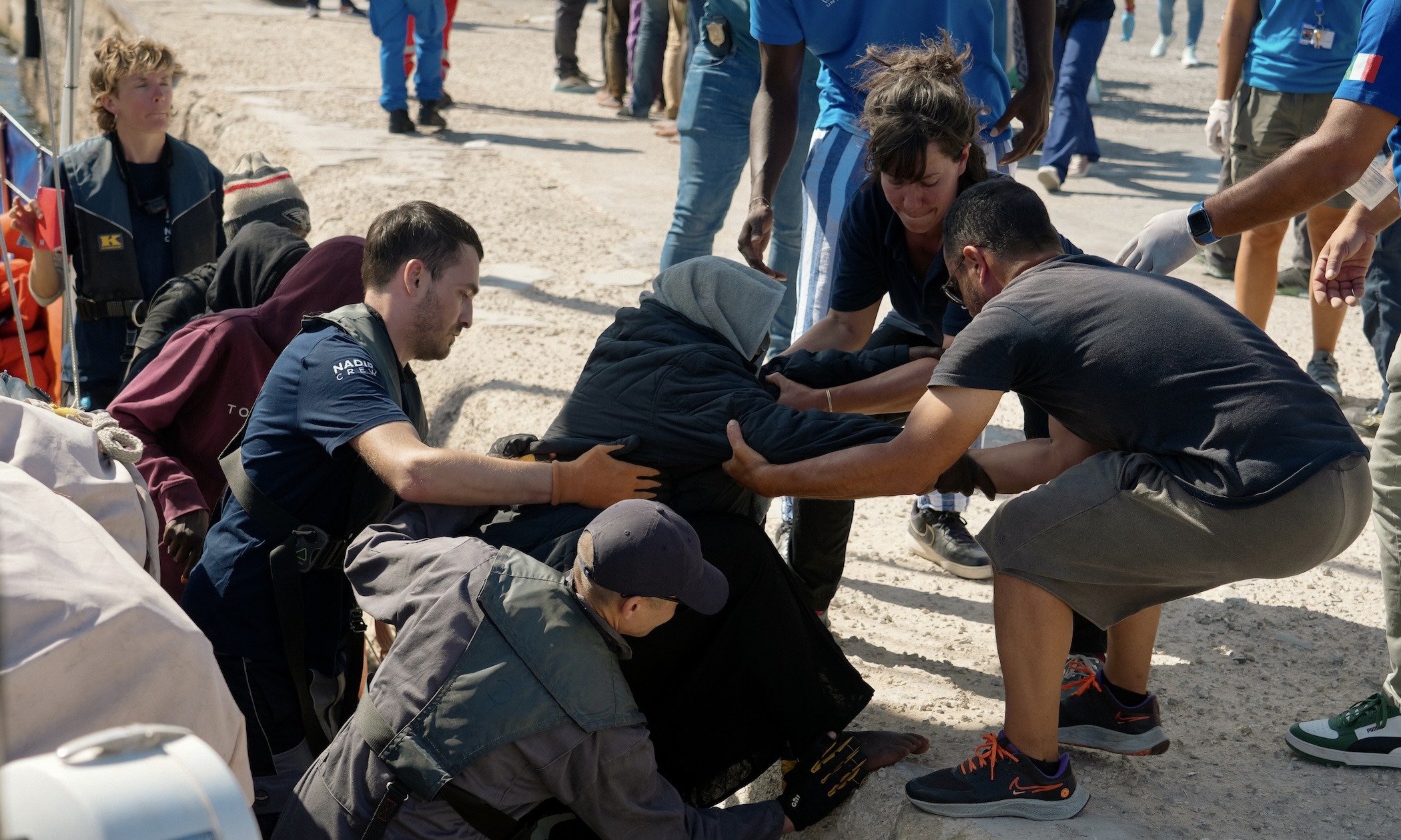 Überlebende gehen an Land im Hafen von Lampedusa.