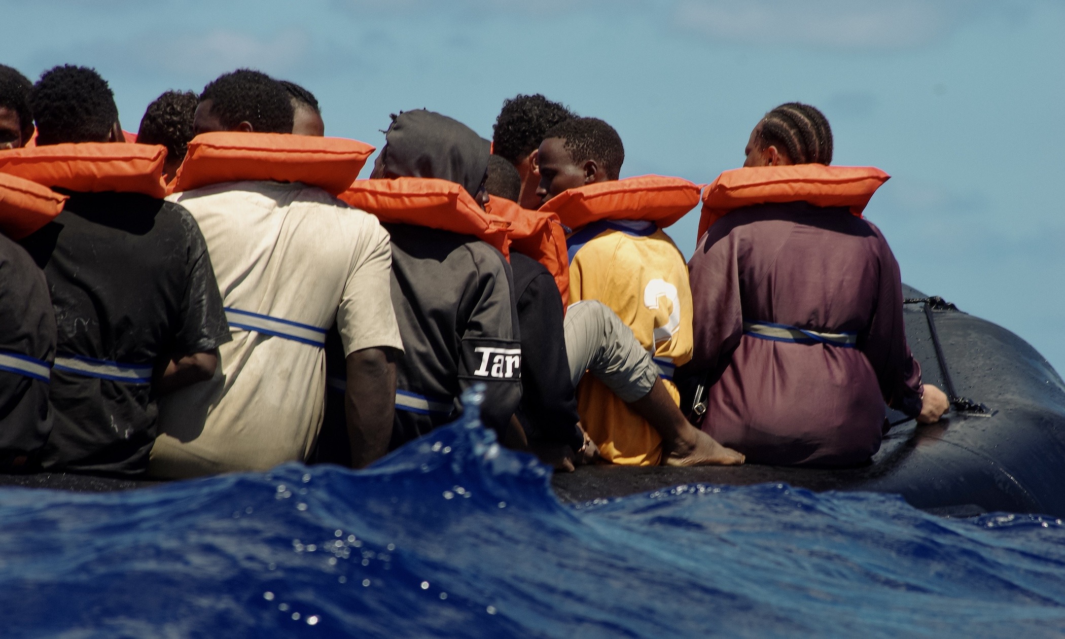 Flüchtende auf einem seeuntauglichen Boot bei hohem Wellengang nachdem die Crewmitglieder der NADIR ihnen Rettungswesten überreicht und Trinkwasser verteilt haben