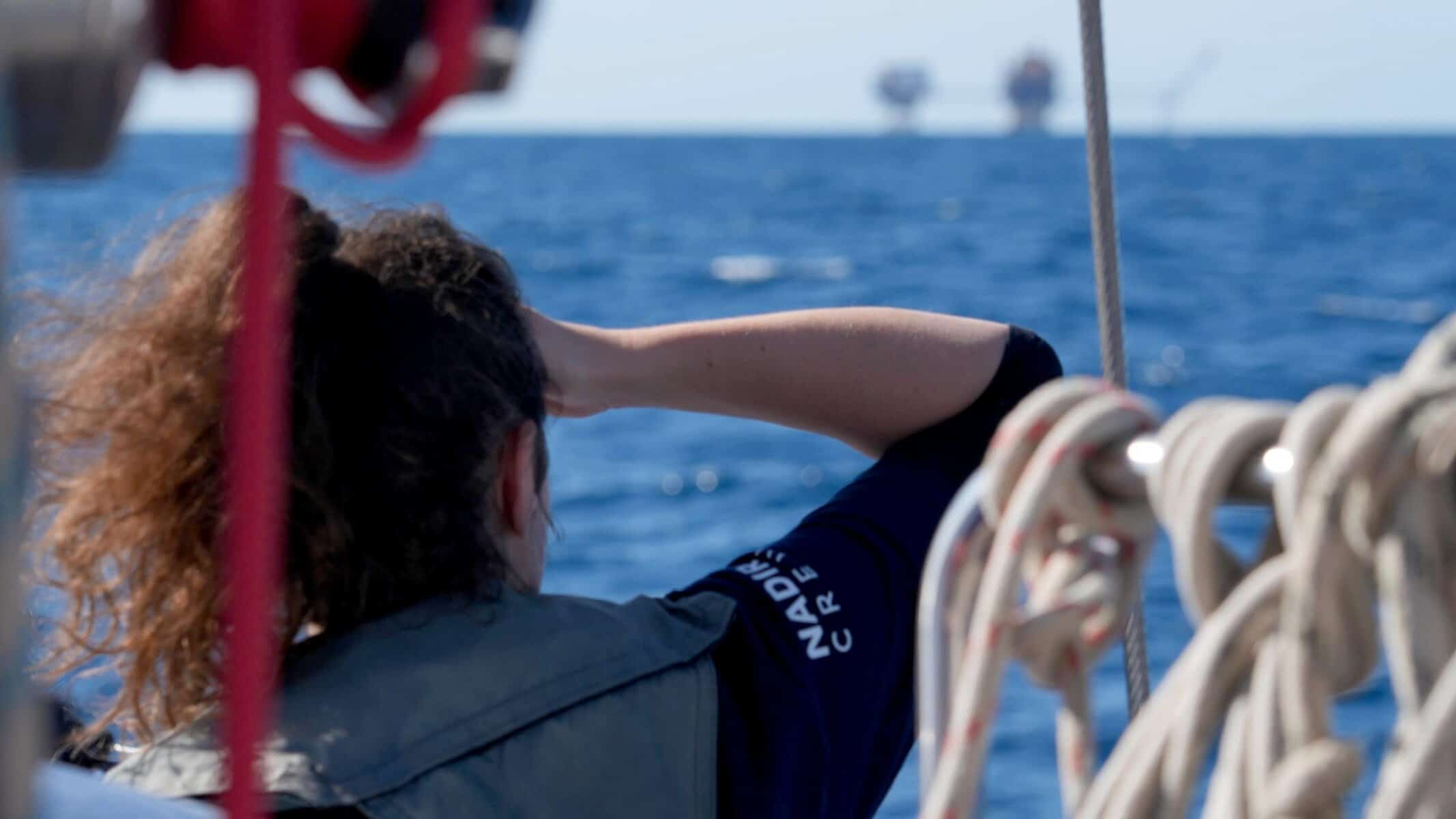 Crewmitglied der NADIR schaut über das Meer in Richtung entfernter Gasplattform Miskar.