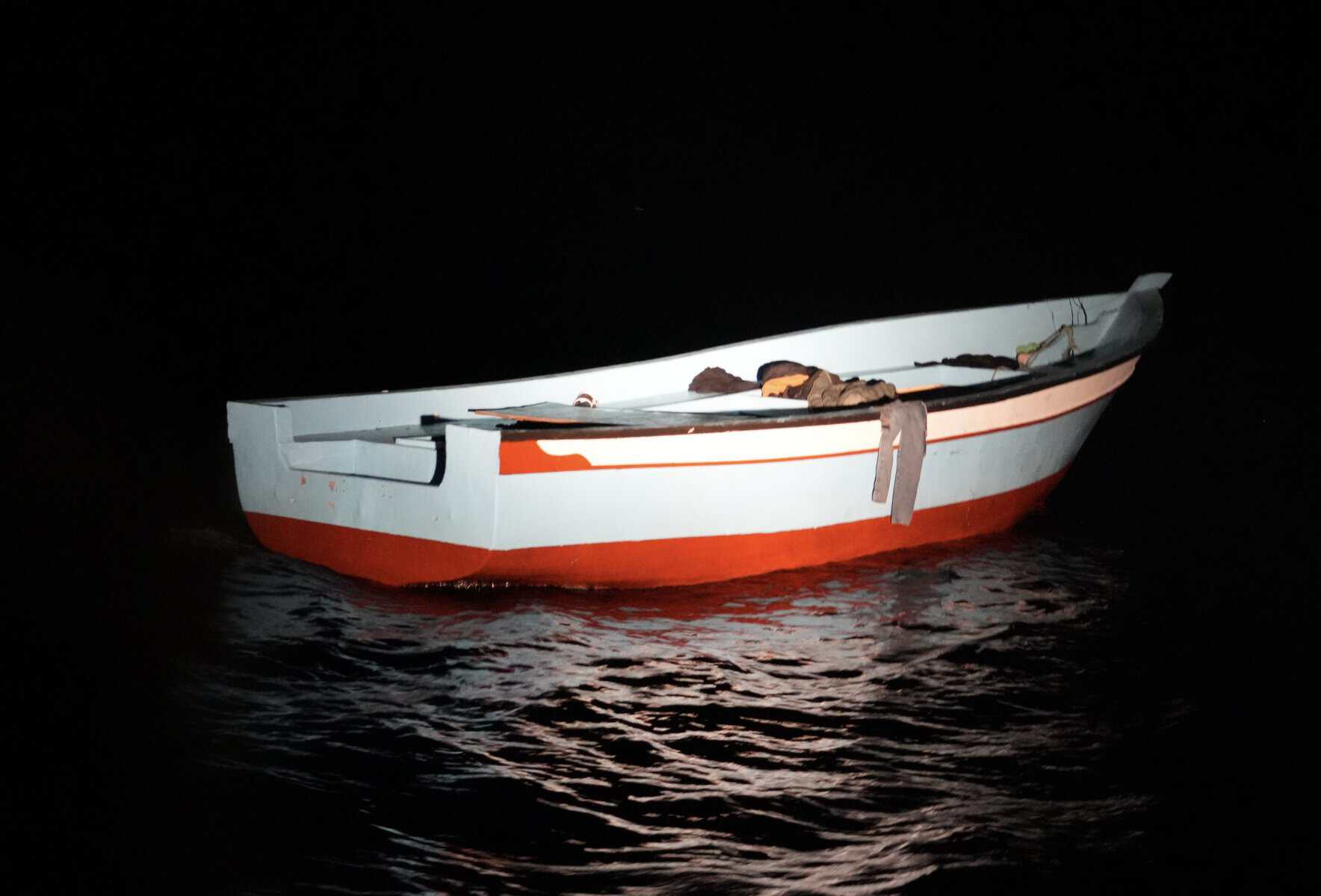 Leeres Holzboot mit Klamotten über Reling bei Nacht. 