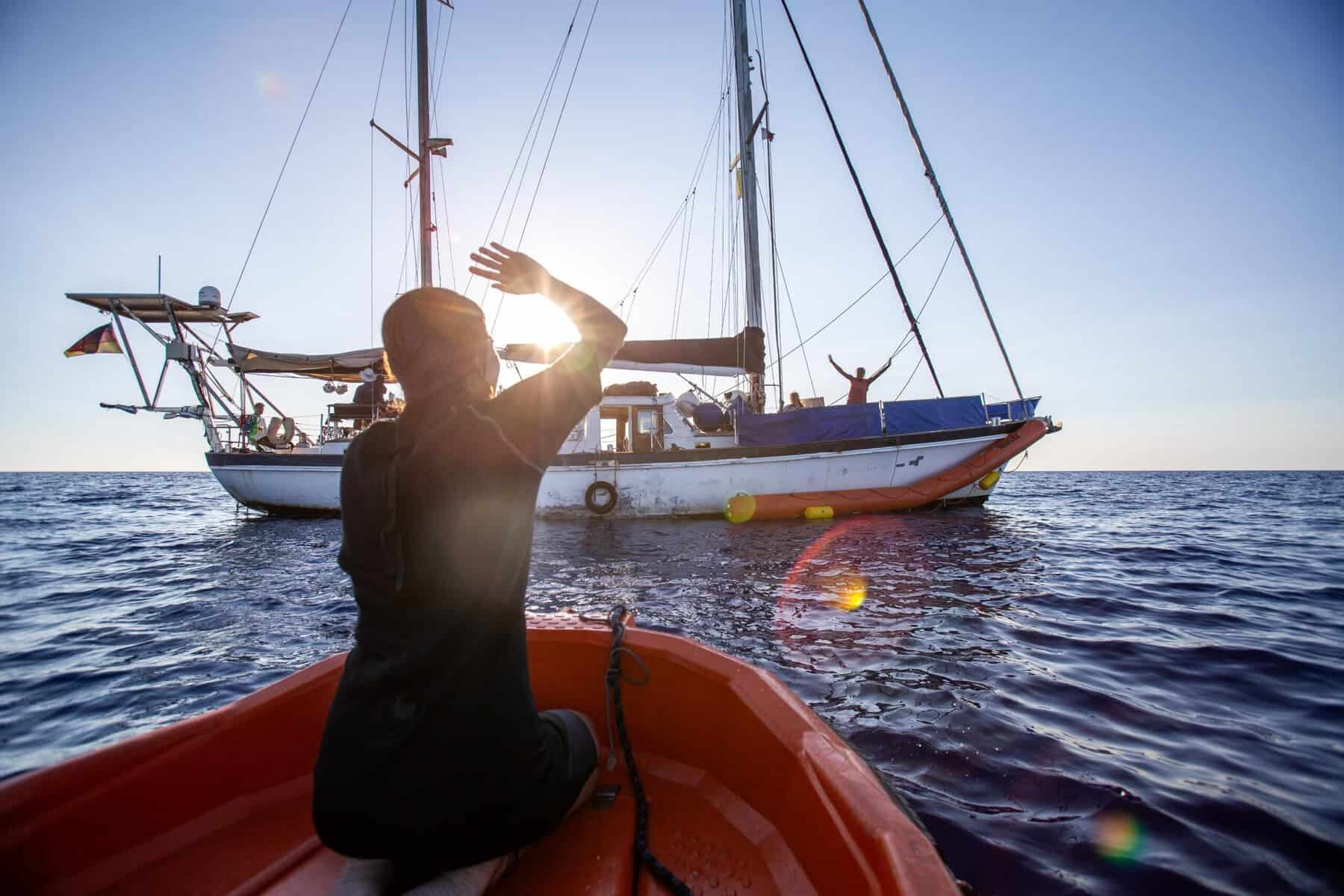 Crewmitglied auf kleinem Boot schaut auf Nadir, wo weitere Crew Mitglieder zu sehen sind